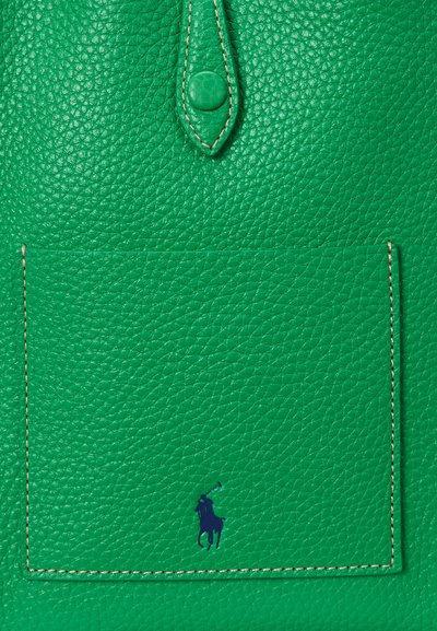 Grön texturerad läderficka med beige sömnad och liten marinblå polo-spelarlogo nära botten i mitten av fickan.