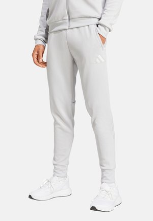 Hellgraue Sporthose mit slim fit, ausgestattet mit Seitentaschen und einem geprägten Drei-Streifen-Logo auf dem Oberschenkel. Weicher Stoff.