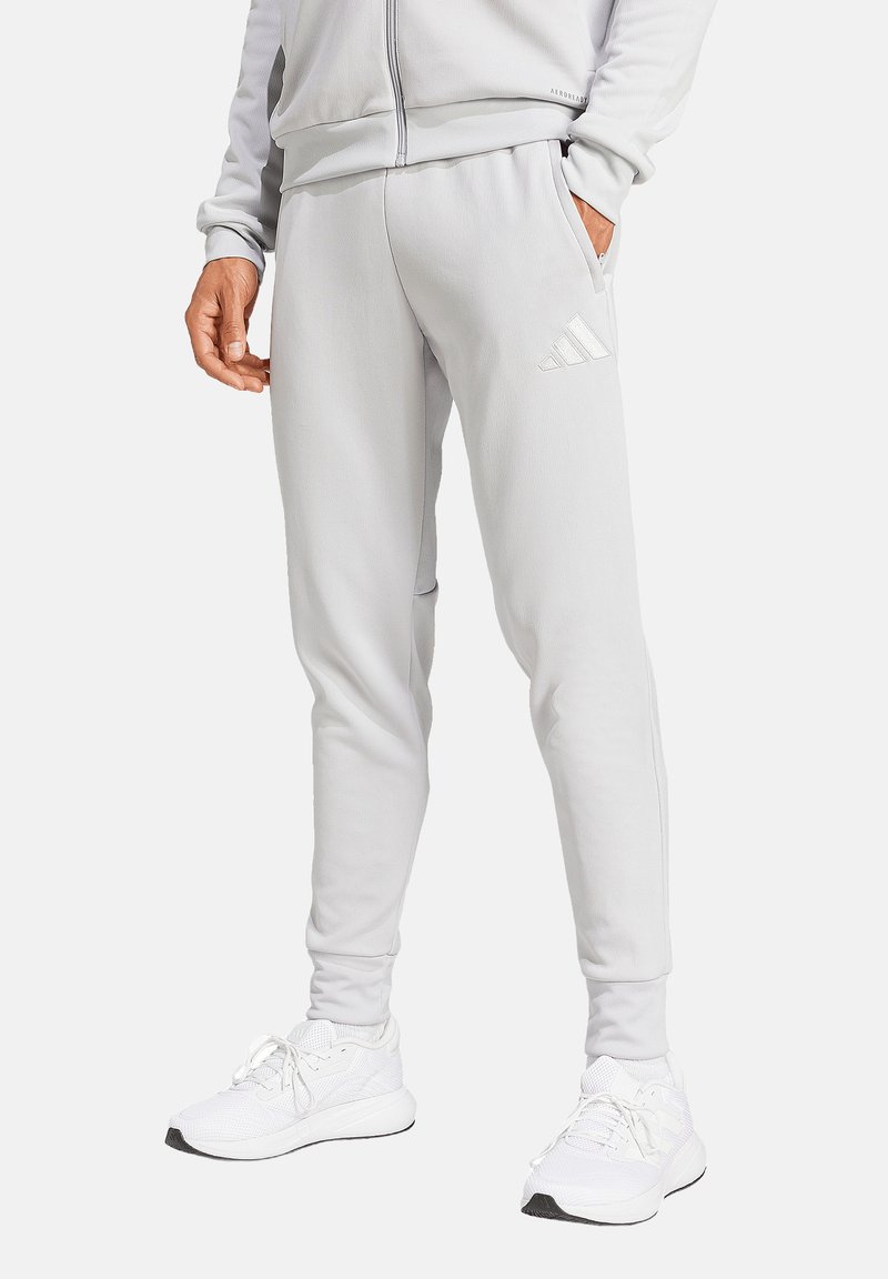 Lichtgrijze sportbroek met een slanke pasvorm, voorzien van zijzakken en een verhoogd drie-strepen logo op de dij. Zachte textuur.