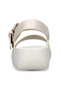 Beige sandaal met twee verstelbare banden en gespdetails. Witte zool met een ronde vorm en een gestructureerde afwerking. Minimalistisch ontwerp.