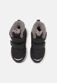Schwarze Kinderschuhe mit zwei Klettverschlüssen, aus synthetischem Material, grauem Fleece-Futter und einer weißen Gummisohle. Abgerundete Zehenform.