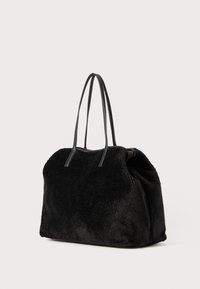 Sort pelsagtig tote-bag med to lange læderhåndtag, rund facon, blød fremtoning og rummeligt interiør.