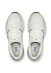 Hvide sportssko med et tekstureret netoverdel, blå accenter og en afrundet silhuet. Har snørebånd og en polstret sål.