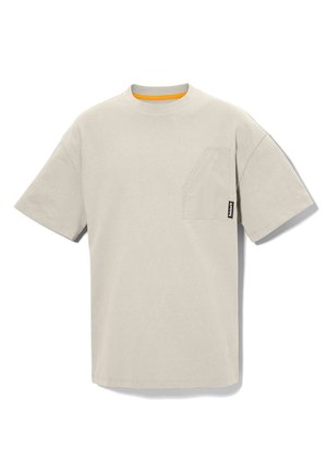 Jasnobeżowy T-shirt z krótkim rękawem, okrągłym dekoltem, asymetryczną kieszenią na piersi po lewej stronie oraz małą czarną metką marki na kieszeni.