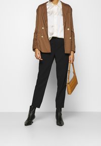 Brun rutig blazer, krämfärgad satin skjorta, svarta skräddarsydda byxor, svarta ankelstövlar och en tan kviltad handväska.