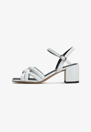 Witte leren blockhak sandalen met een geweven bandontwerp en een verstelbare enkelriem. Heeft een contrasterende zwarte binnenzool.