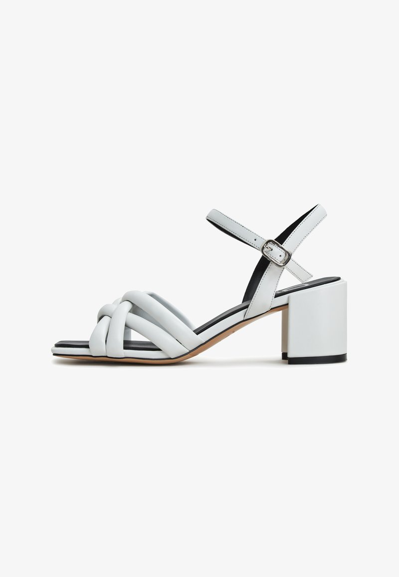 Sandales à talons blocs en cuir blanc avec un design de bande tissée et une bride de cheville ajustable. Elles présentent une semelle intérieure noire contrastante.