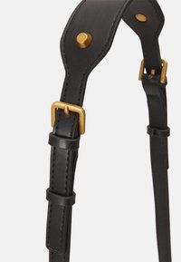 Sangle en cuir noir avec des accents en métal doré, présentant une boucle et des détails de couture, conçue pour la durabilité et l'ajustabilité.