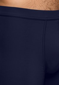 Costume de baie bleumarin dintr-un material neted și elastic. Are un design ajustat, cu un talie groasă și detalii de cusătură minime.