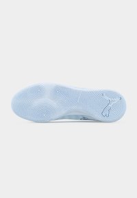 Semelle d'une chaussure de sport blanche avec des motifs d'adhérence circulaires texturés et un logo Puma stylisé près du talon.