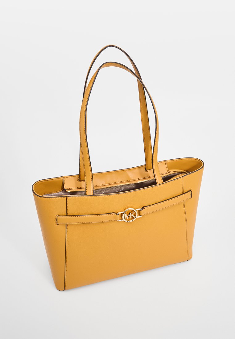 Sac fourre-tout en cuir jaune avec des doubles poignées, une sangle décorative à l'avant arborant un logo circulaire doré, et une forme structurée.