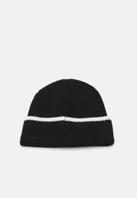 Bonnet en tricot noir avec une texture côtelée et une bande horizontale blanche. Présente un dessus arrondi et un revers replié.