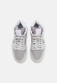 Šedé a bílé vysoké tenisky s perforovanou špičkou, texturovanou kůží a plochými šňůrkami. Obsahují logo na jazyku a polstrování kolem kotníku.