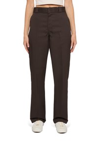 Bruna raka byxor med flat framsida, bältesöglor och sidofickor, tillverkade av ett mjukt tyg. Bärs med ljusa sneakers.