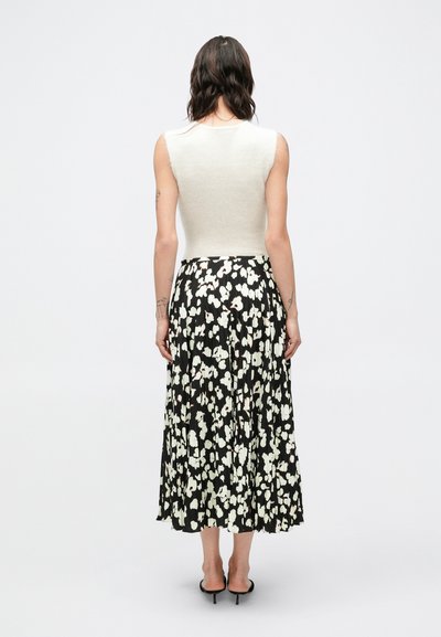 Svetlosivý tielkový top v kombinácii s čiernou plisovanou maxi sukňou s kvetinovým vzorom v bielej a krémovej farbe. Hladká textúra látky a splývavý dizajn.
