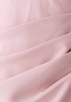 Tessuto intrecciato di colore rosa chiaro con superficie morbida e testurizzata, caratterizzato da pieghe orizzontali che creano profondità e interesse visivo.