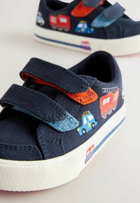 Barns marinblå canvas skor med två kardborreband. Har broderade fordon i röd, blå och grön på sidan och en strukturerad gummisula.