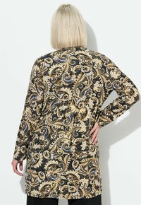 Tunica a maniche lunghe in tessuto nero con un intricato motivo paisley in oro e bianco; vestibilità rilassata, lunghezza media, texture morbida, orlo arrotondato.