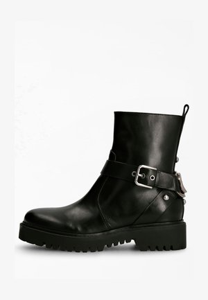 Bottine en cuir noir avec un bout arrondi, détail de sangle à boucle et semelle en caoutchouc épaisse avec un profond relief pour une meilleure adhérence.