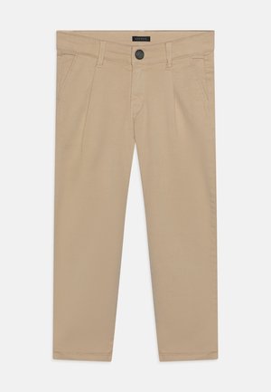 Beige bukser med flad front, bæltestropper, sidelommer, knaplukning og sømmet kant på ensfarvet baggrund.