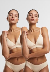 Beige seamless bra with triangular cups and thin straps, paired with matching high-waisted briefs. Smooth texture and minimalistic design.