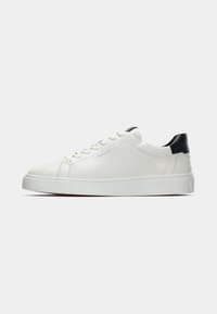 Adidași din piele albă, cu vârf rotund, design cu șireturi și accente negre la călcâi. Prezintă o talpă din cauciuc alb texturat și detalii de cusătură.