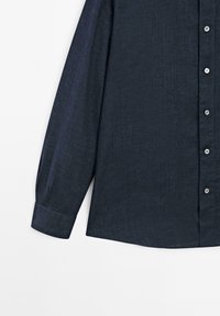 Long-sleeve dark blue button-up shirt with visible cuff and six small white buttons on a white background.