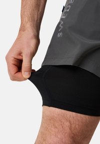 Zwarte sportshorts met een grijze buitenlaag. De textuur is glad en aansluitend, gemaakt van ademend materiaal met zichtbare stiksels.