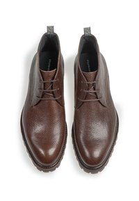 Zapatos de cuero marrón con cordones, acabado texturizado, punta redonda y suela de goma oscura contrastante. Presentan una lengüeta en el talón.