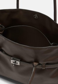 Torba na ramię z ciemnobrązowej skóry, z otwartą górą, wewnętrzną kieszenią, dwoma uchwytami oraz srebrnym zapięciem na przednim pasku.