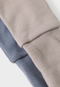 Two sweater sleeves, one in light beige and one in dark blue, made of textured knit fabric. Edges are hemmed and slightly rolled.