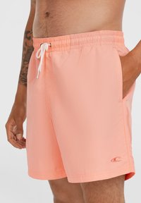 Őszibarack színű fürdőshorts elasztikus derékkal, fehér zsinórral, oldalsó zsebekkel és diszkrét logóhímzéssel az alján. Könnyű anyag.