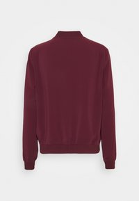 Burgundská bunda, hladká tkanina, žebrovaný límec a manžety, elastický pas, minimalistický design, žádná viditelná logo ani vzory.