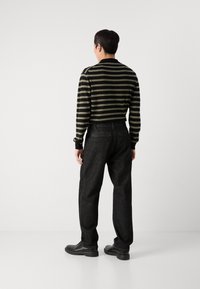 Pulover striped negru și măsliniu, cu guler rotund, asociat cu blugi închiși, cu croială lejeră, și pantofi negri. Design simplu și culori neutre.