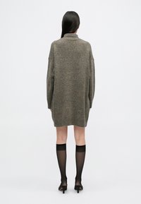 Üks suur ja soe kudum hall-pruuni värvusega, millel on kõrge krae ja langetatud õlad, koos läbipaistvate mustade kõrgete sukade ja kontsakingadega.