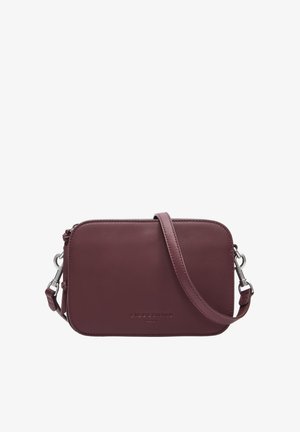 Burgundy leather crossbody bag with a smooth texture, rounded edges, zip closure, adjustable strap, and embossed brand name on the front.