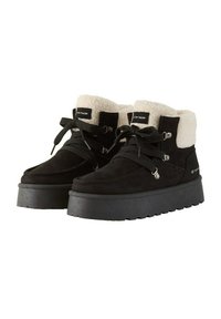 Zwarte suede plateau laarzen met een pluizige crème nepbont omslag, voorzien van dikke zwarte veters en zilveren hardware accenten.