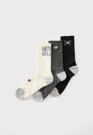 Drei New Balance Crew-Socken in Weiß, Dunkelgrau und Schwarz mit grauen Zehen und Logo-Patches an Bündchen und Füßen.