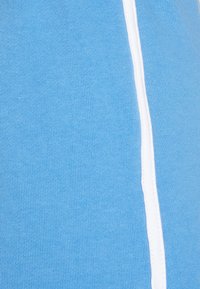 Tecido azul claro com uma textura rígida e um detalhe de risca branca vertical ao longo de um lado. O material aparenta ser macio e elástico.