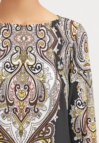 Haut à manches longues avec un motif cachemire multicolore en rose, jaune et noir. Tissu lisse avec un col bateau.