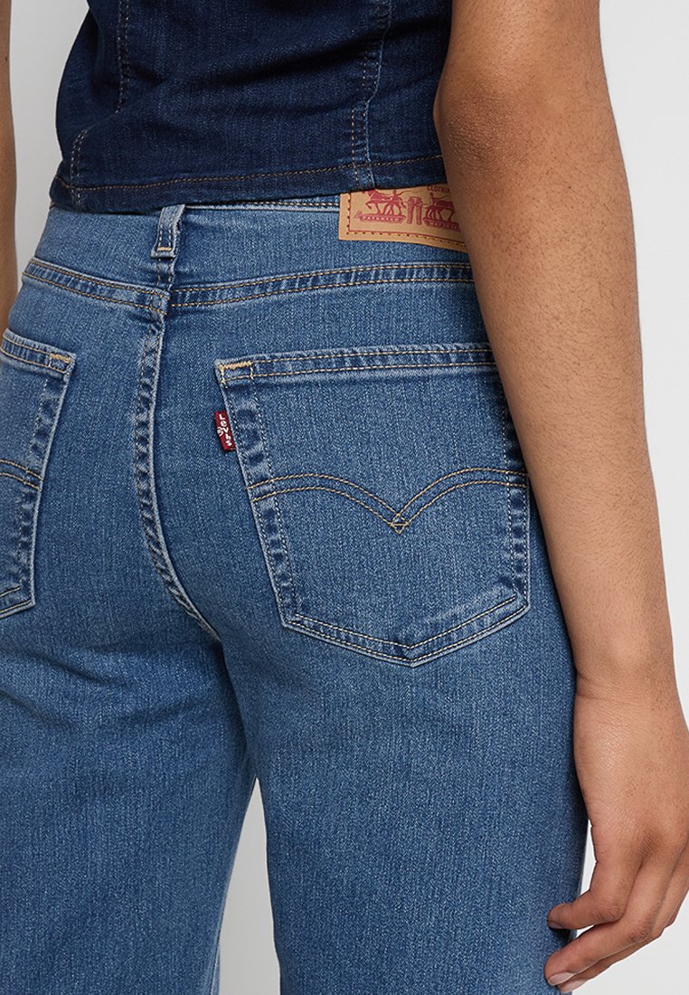 Jeans in denim blu con una vestibilità attillata, dotati di due tasche posteriori e un'etichetta classica in pelle marrone in vita.
