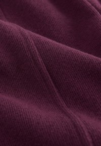 Material burgundy cu un model texturat cu dungi. Suprafețe moi, calde și ușor pufoase, cu linii subtile și neregulate.