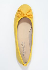 Žluté semišové baletní byty s propletenou mašlí na špičce a béžovou polstrovanou stélkou, pohled zeshora.