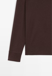 Bruine lange mouwen shirt met ronde hals, gemaakt van zacht katoen. Heeft een rechte onderrand en aangesloten manchetten.