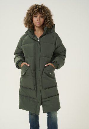 Lange, volumineuze groene parka met een capuchon, gevoerd ontwerp, twee voorzakken en een ritsluiting. Zacht materiaal met een gestructureerde afwerking.