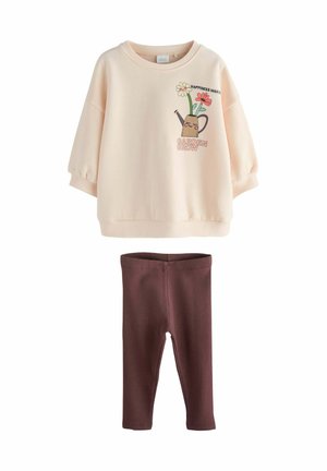 Kremowa koszula z długim rękawem z grafiką konewki i kwiatów, połączona z brązowymi, prążkowanymi legginsami.