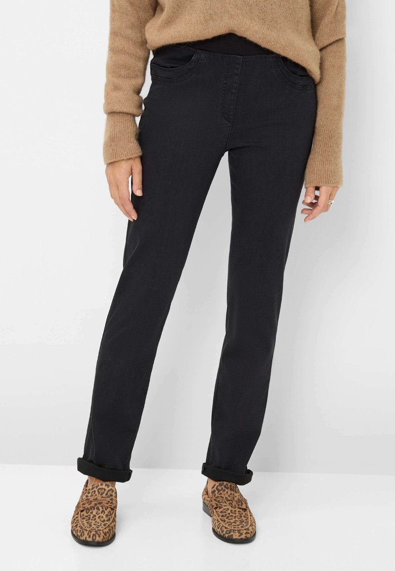 Schwarze Baumwolljeans mit geradem Bein, ausgestattet mit Vordertaschen und aufgerolltem Saum, kombiniert mit braunen Schuhen im Leopardenprint.