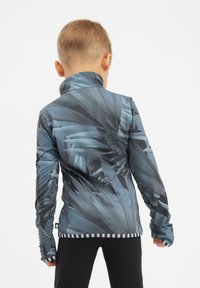 Langarmiges, blaues und schwarzes Sportshirt mit geometrischem Muster, hohem Kragen und gestreiftem Saum an Taille und Ärmeln.