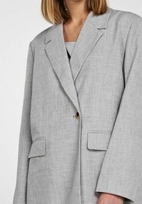 Szary lniany blezer z klapą z wycięciem, pojedynczym zapięciem na guzik, dwoma przednimi kieszeniami oraz luźnymi rękawami.