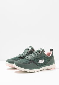 Gröna mesh-sneakers med rosa accenter. Har en rund tå, texturerade överlägg och en dämpad sula. Sidologotyp synlig.